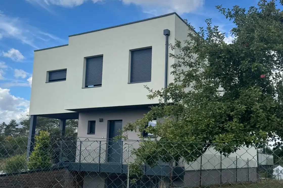 Façade sud d’une maison contemporaine couverte d’un enduit de finition clair.