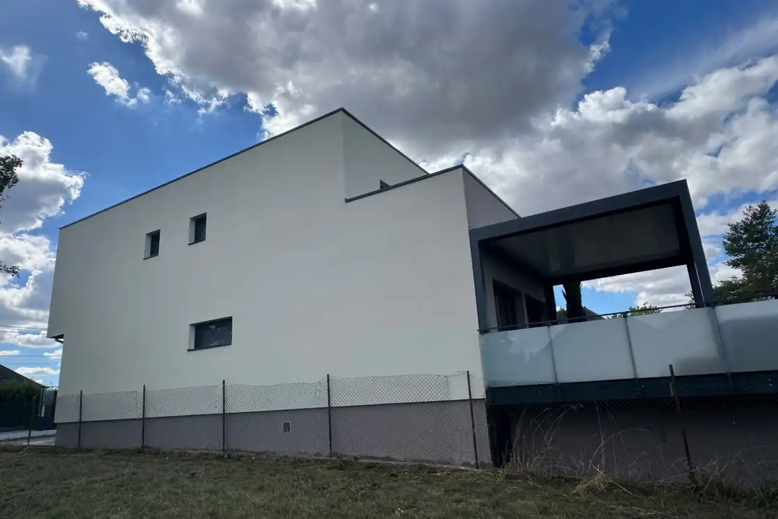 Pignon d’une maison contemporaine après enduit de finition blanc cassé, menuiseries anthracite