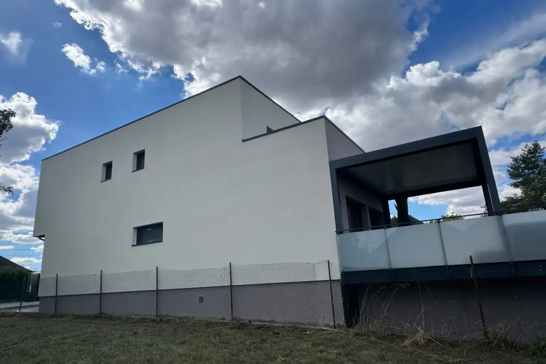 Pignon d’une maison contemporaine fini avec un enduit blanc cassé sur support isolé.